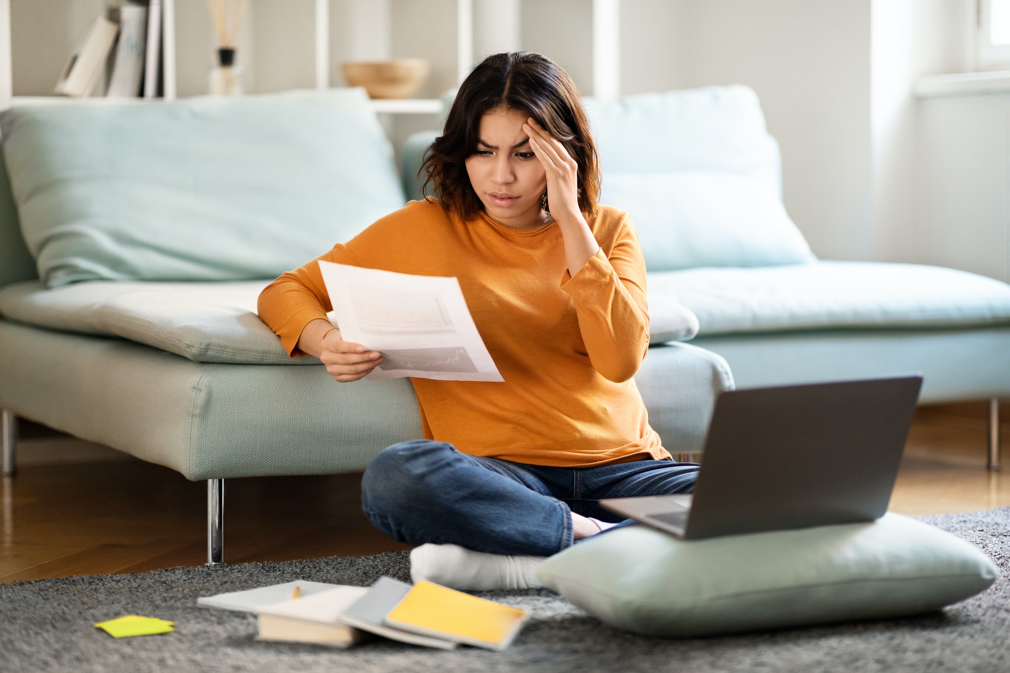 Stressed Arab Female Freelancer Working With Papers And Laptop At Home