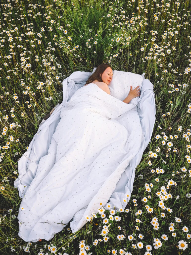 a beautiful girl sleeps in a flower field in summer by country