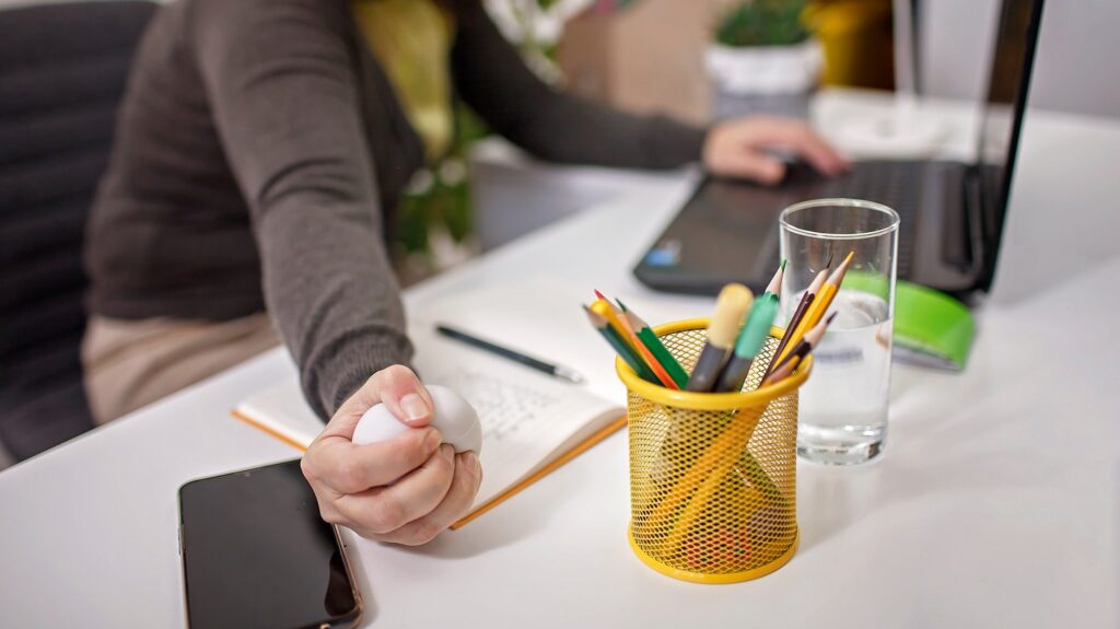 Woman squashing anti stress ball in her hand to reduce stress during online conference in lockdown