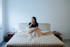 Young Woman Sitting on Bed, Battling Loneliness and Nighttime Depression