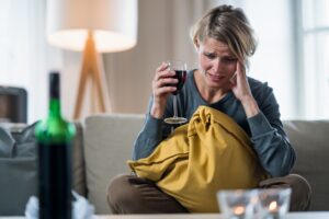 Depressed woman indoors at home, mental health and alcohol addiction concept