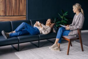 A woman lying on a couch talks about her trauma to a psychoanalyst.