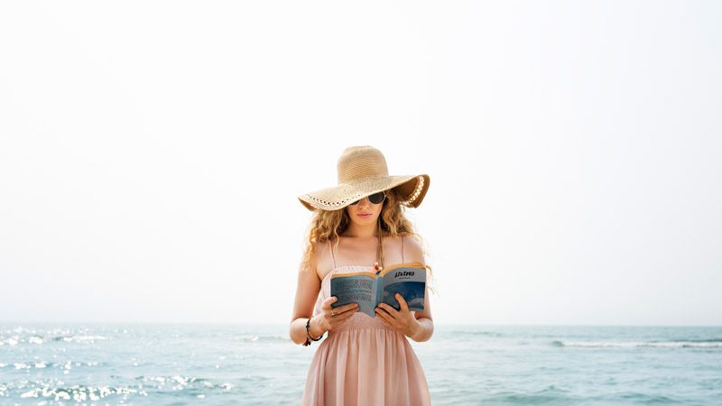 kobieta czytająca książkę na plaży