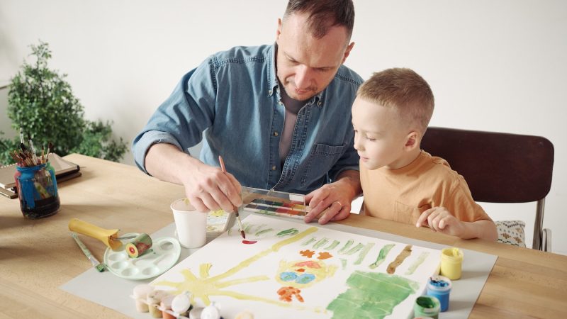 Father helping his son to paint a picture
